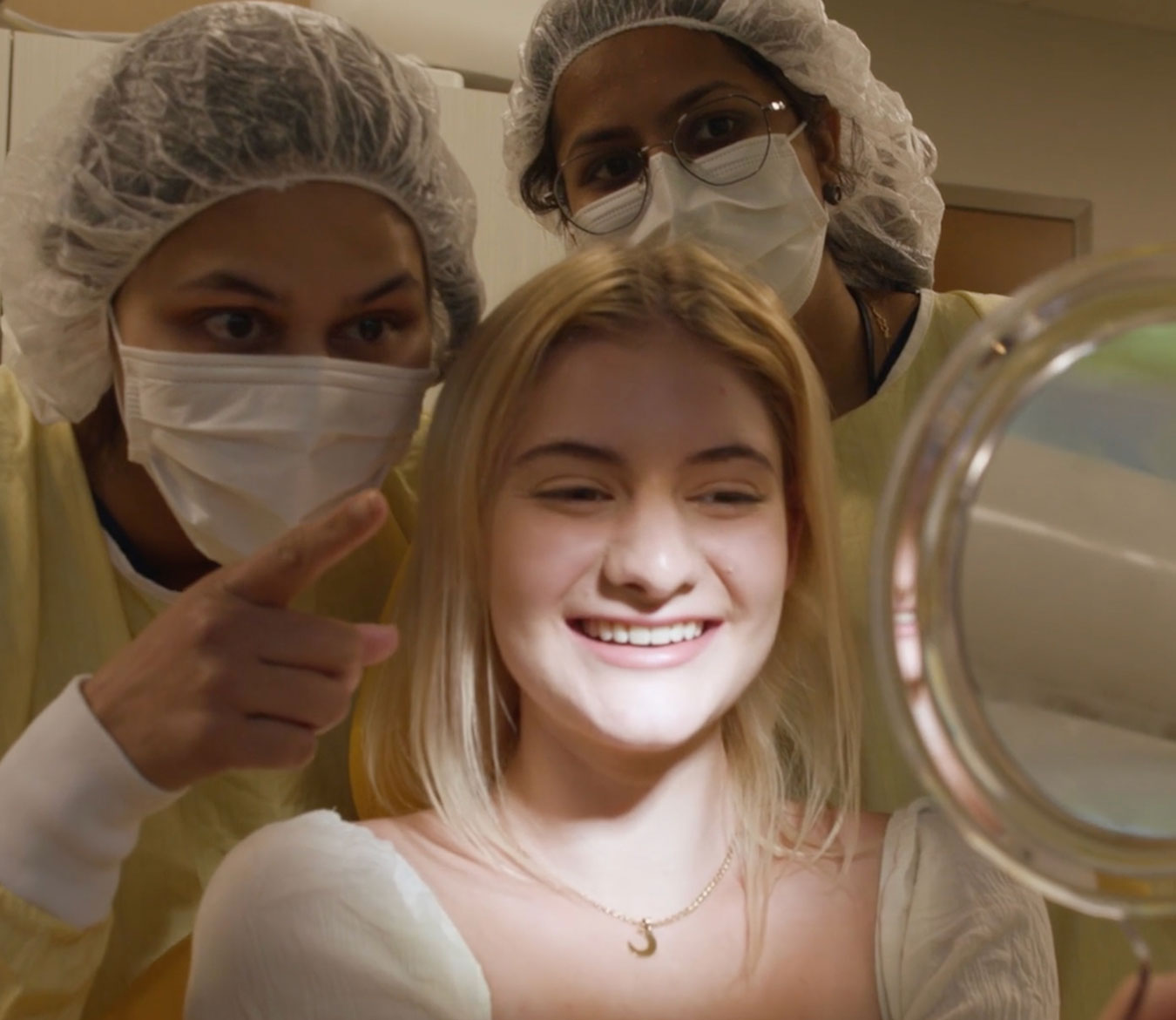 Orthodontics patient looking at smile in mirror next to orthodontists.