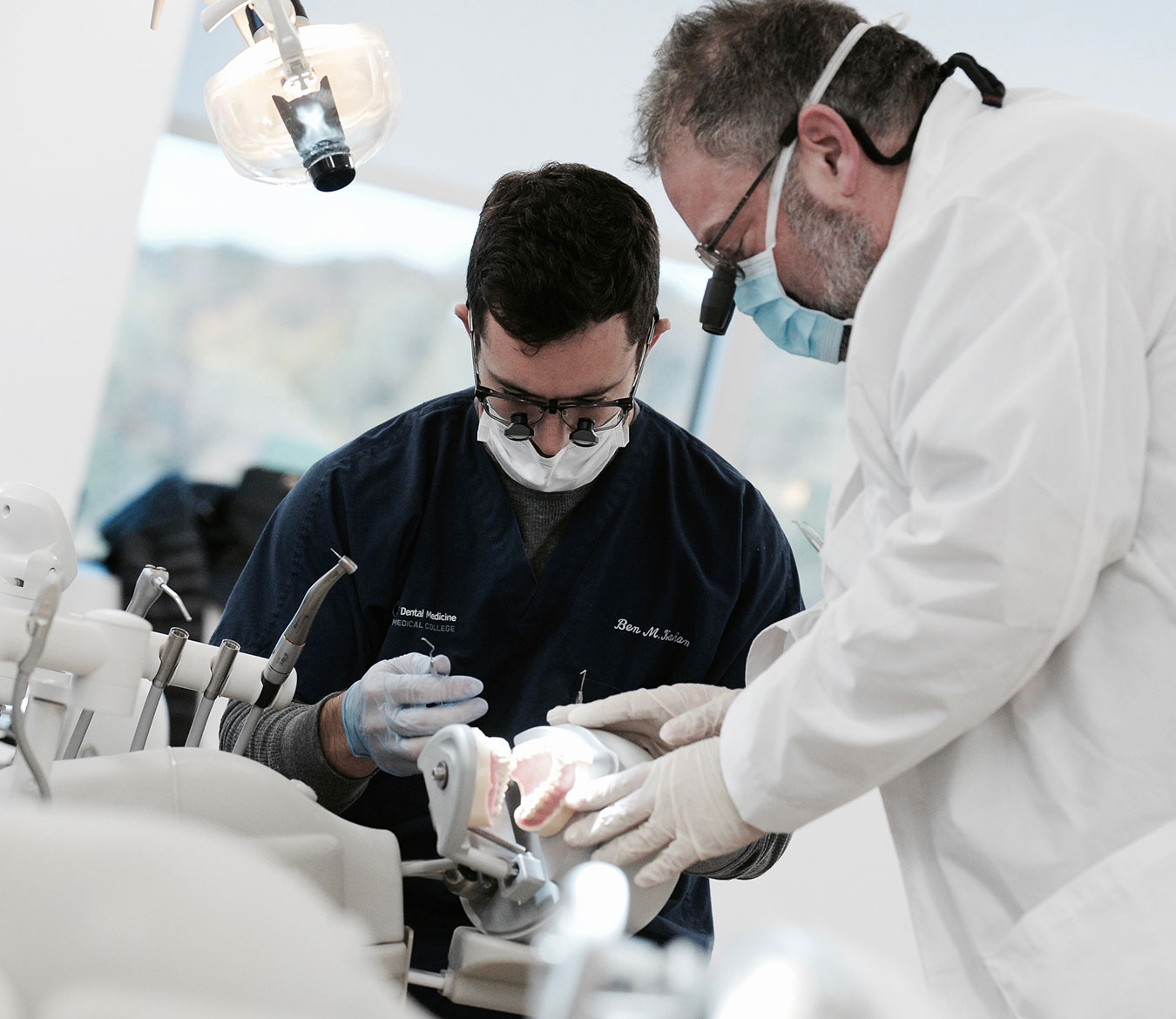 Professor and student working on dummy together in classroom.